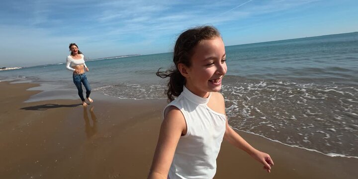 A mother and her daughter are running and enjoying on the beach