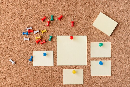 Colorful Push Pins and Blank Sticky Notes Arranged on a Cork Board Background Highlighting an Organized Workspace and Creative Planning Environment