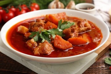 Delicious cooked stew in bowl on wooden table, closeup