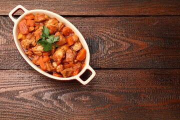Delicious cooked stew in baking dish on wooden table, top view. Space for text