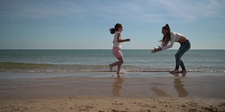 A mother and her daughter are running and enjoying on the beach