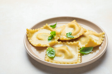 Delicious ravioli with basil on light table, closeup