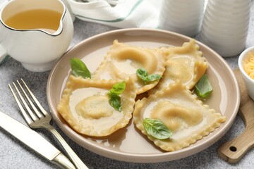 Delicious ravioli with basil served on light grey table, closeup
