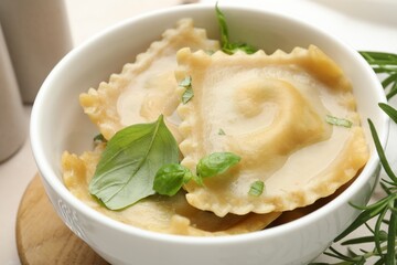 Delicious ravioli with basil in bowl on table, closeup