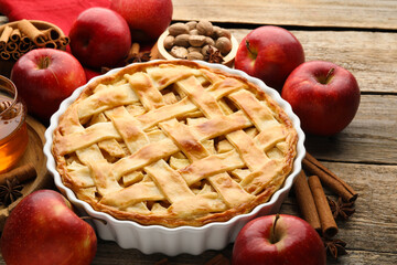 Tasty homemade apple pie and ingredients on wooden table, closeup