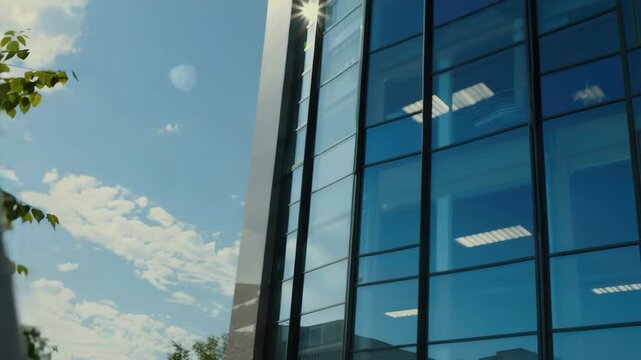 Man wearing a business suit and tie is smiling while using a cell phone. He stands on the street with a modern glass building behind him under a blue sky with clouds.