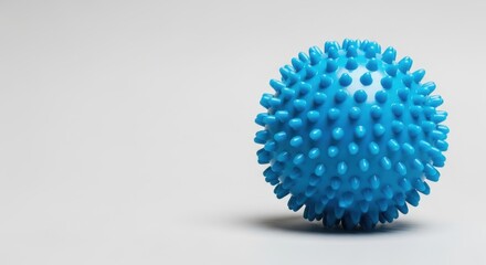 A blue spiky massage ball for muscle relief sits against a clean grey background in a simple composition