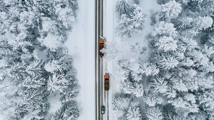 Aerial View of Snow-Covered Road with Winter Plows Clearing Path Through Snowy Forest Landscape