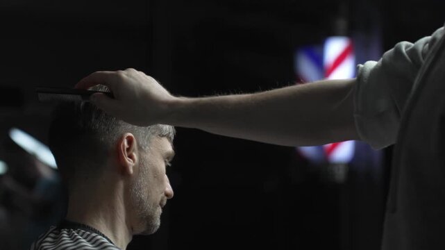 Professional barber carefully checking customer's hair texture and head contours, preparing for precise haircut, vintage barbershop interior with iconic striped pole visible