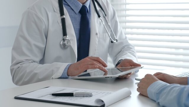 Medical practitioner sharing information with patient on a digital tablet during consultation, enhancing communication in healthcare. Medicine and health care concept