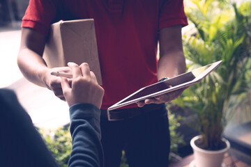 A person wearing red T-shirt is delivering parcels to a satisfied client. Friendly worker