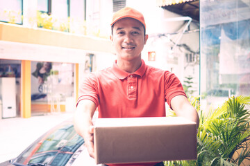 A person wearing red T-shirt is delivering parcels to a satisfied client. Friendly worker