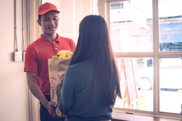 A person wearing red T-shirt is delivering parcels to a satisfied client. Friendly worker
