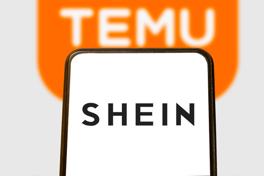 Warsaw, Poland - November 8, 2025: Close-up of a SHEIN logo displayed on a phone screen, in focus, with a TEMU logo blurred in the background, illustrating e-commerce branding.