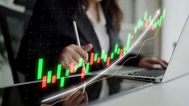 A business professional analyzes financial data using technology in a modern office. The stock market chart displays growth trends and investment performance metrics. Copula