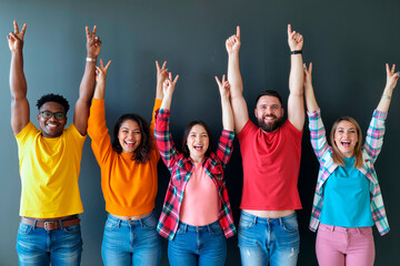 Group of diverse young adults standing in row raising arms and making peace signs, smiling and looking at camera against plain background, showing cheerful expressions