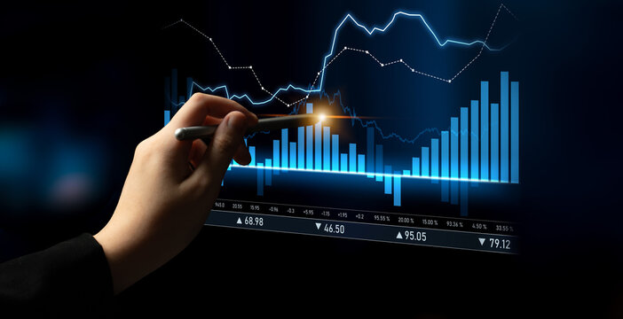 A hand with a pen analyzes a digital stock chart displaying blue graphs and data trends, illustrating financial analysis and investment strategy in an office setting. Scalp
