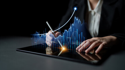 A business professional engages with a tablet to examine financial market trends, surrounded by digital graphs and data visualizations in a dark workspace. Scalp