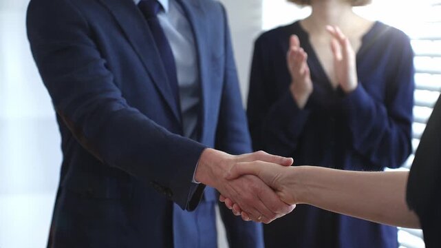 Business people shaking hands, concluding a deal, and celebrating success with an agreement and partnership in a corporate office environment