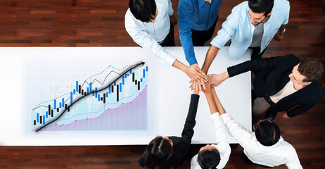 A collaborative team meeting where hands unite over a table, with visual graphs of business growth in the background, emphasizing strategy and teamwork. Axiom