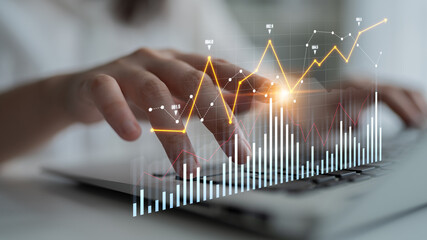 A business professional analyzes trends on a laptop, showcasing hands engaging with rising...