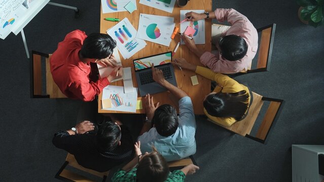 Top view of business team looking at laptop and analyzing chart. Close up of diverse group working on computer and reading financial report. Group of people explain idea at meeting. Convocation.