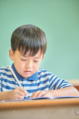 Naklejka premium 学校で勉強をする小学生の男の子