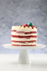 Delicious sponge cake with Christmas decor and red currants on white wooden table against grey background, closeup