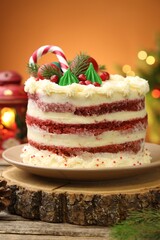 Tasty cake with Christmas decor on wooden table against blurred lights, closeup