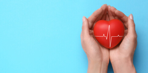 Cardiology. Woman holding red heart with pulse line on light blue background, top view. Banner...