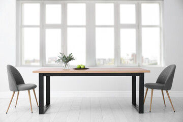 Table and chairs near big window in room. Interior design
