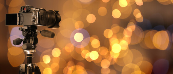 Professional camera against blurred background with bokeh lights. Banner design