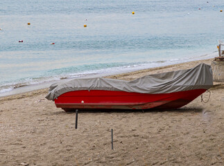 Skiff boat covered with plastic parked on beach send during winter