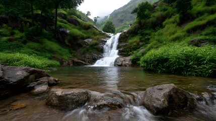 Obraz premium A lush green waterfall cascades down rocky slopes into a clear serene pool surrounded by vibrant foliage