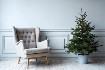 Neutral colored high backed armchair sits beside a potted evergreen tree against a paneled wall