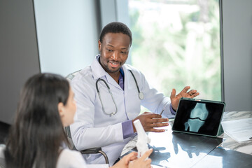 Professional doctor showing an x-ray result to a patient in a modern clinic office, discussing diagnosis and treatment options with digital healthcare technology and professional consultation.