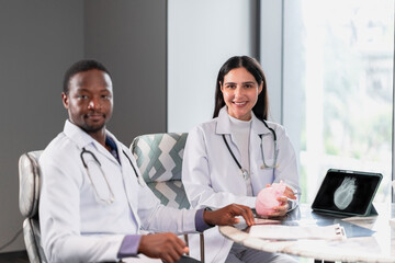 Two professional doctors working together with a heart model and tablet in a modern clinic office, showing teamwork, digital healthcare innovation, and professional medical education.