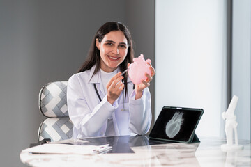 Smiling female doctor holding a heart model for medical education in a modern clinic office, explaining healthcare and treatment using digital technology and professional communication.