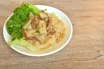 stir fried large noodles with chicken and crispy pickled squid with scent of burning kitchen pan on dish 