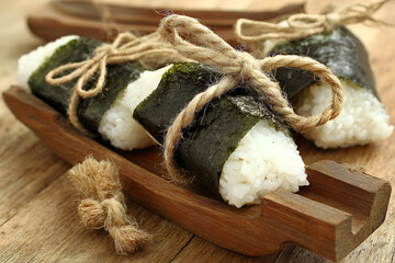 Onigiri rice balls wrapped in nori on rustic wooden table, beautifully presented