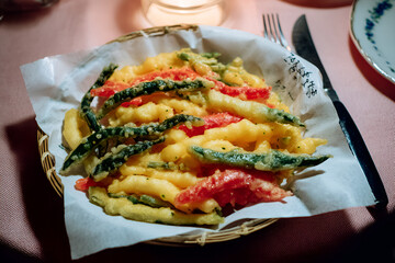 Crispy tempura vegetables served in paper lined basket, showcasing vibrant colors and textures