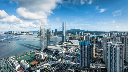 Naklejka premium Aerial view of the modern urban cityscape with a famous bridge and commercial skyscrapers on a sunny day in Macau.