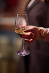 Refined woman savoring amber glass drink, Closeup of woman enjoying sophisticated wine experience, Fashionable lady gracefully holding glass of golden wine at classy