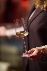 Refined woman savoring amber glass drink, Closeup of woman enjoying sophisticated wine experience, Fashionable lady gracefully holding glass of golden wine at classy