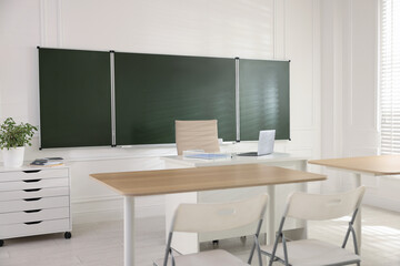 Green chalkboard and stylish furniture in classroom. Mockup for design