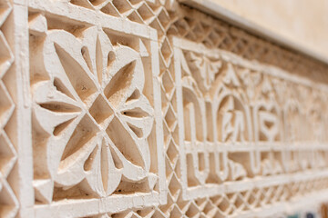 Detailed close-up of intricate star-shaped Islamic stucco work inside the Mausoleum of Moulay Ismail in Meknes, Morocco, highlighting craftsmanship and geometric patterns.


