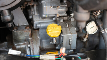 Fuel storage tank of machine engine or vehicle engine with refuel symbol on yellow cap. Industrial equipment object, close-up.