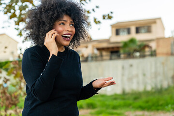 Black woman talking smartphone expressing happy surprise
