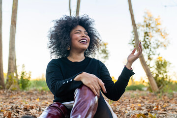 Black woman laughing connecting with nature in autumn