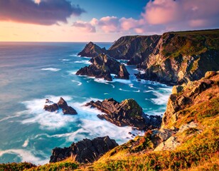 Coastal cliffs with rugged rock formations meet the ocean under a pastel-colored sunset sky